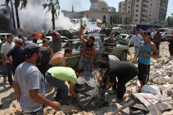People react as they remove a dead body from the scene of an explosion outside one of two mosques in Lebanon's northern city of Tripoli,