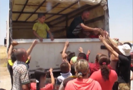 Christian refugees, who fled or were expelled from Mosul, crowd around a truck distributing food aid
