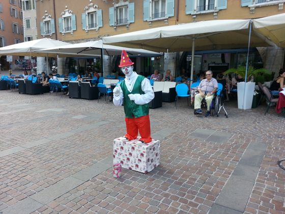 En klovn som underholder med stil er hyggelig på et stort torg.
