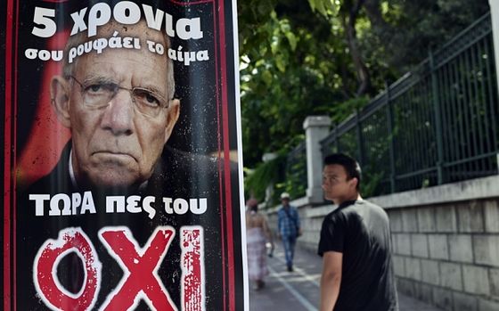 A pedestrian looks at a poster depicting German Finance Minister Wolfgang Schauble and reading 