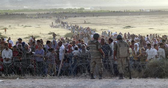 turkish-soldiers-stand-guard-syrian-refugees-wait-behind-border-fences